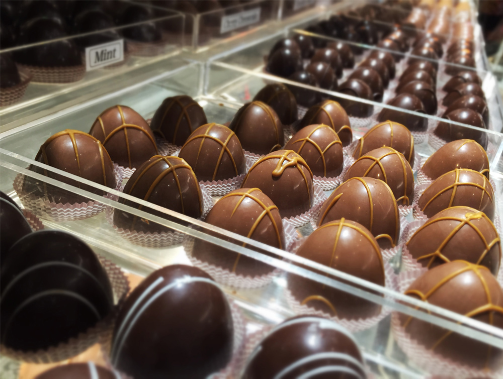 Chocolate truffles arranged in a glass display case at Sweet Chico Confections